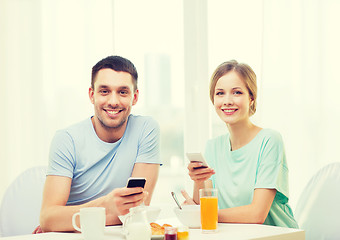 Image showing smiling couple with smartphones reading news