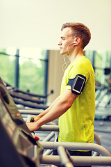 Image showing man with smartphone exercising on treadmill in gym