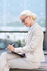 Image showing young smiling businesswoman with notepad outdoors