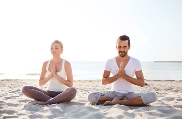 Image showing smiling couple making yoga exercises outdoors