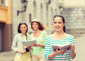 Image showing smiling teenage girls with city guides and camera