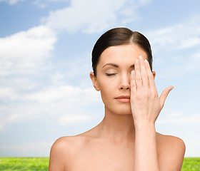 Image showing smiling young woman covering face with hand