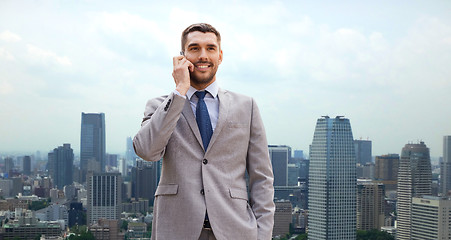 Image showing smiling businessman with smartphone in city