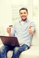 Image showing smiling man working with laptop and credit card