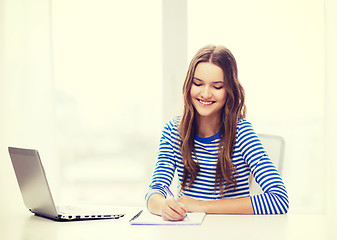 Image showing smiling teenage girl laptop computer and notebook