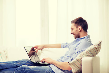 Image showing smiling man working with laptop at home