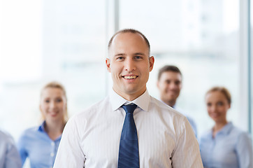 Image showing smiling businessman with colleagues in office