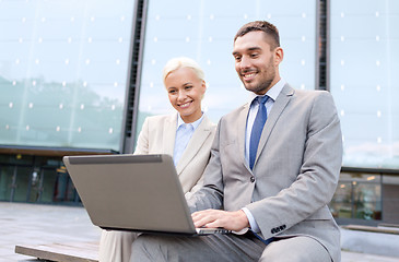 Image showing smiling businesspeople with laptop outdoors