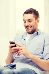 Image showing smiling man with smartphone at home