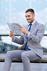 Image showing young smiling businessman newspaper outdoors