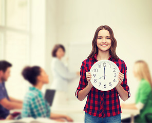 Image showing young woman in casual clothes with wall clock