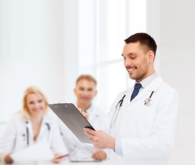 Image showing smiling male doctor with clipboard and stethoscope