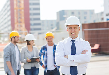 Image showing group of smiling builders in hardhats outdoors