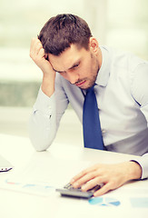 Image showing stressed businessman with laptop and documents
