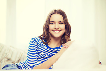 Image showing smiling teenage girl sitting on sofa at home