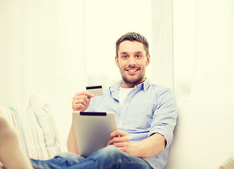 Image showing smiling man working with tablet pc at home