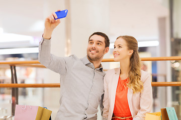 Image showing happy couple with smartphone taking selfie in mall