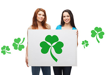 Image showing smiling teenage girls holding board with shamrock