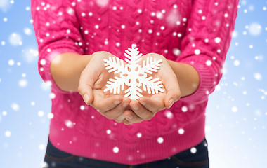 Image showing close up of woman in sweater holding snowflake