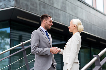 Image showing smiling businessmen shaking hands on street