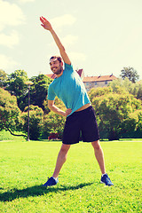 Image showing smiling man stretching outdoors