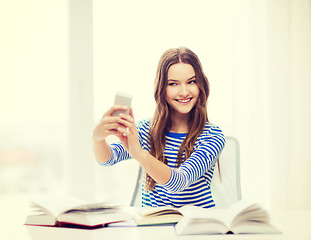 Image showing smiling student girl with smartphone and books