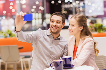 Image showing happy couple with smartphone taking selfie in mall