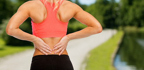 Image showing close up of sporty woman touching her back
