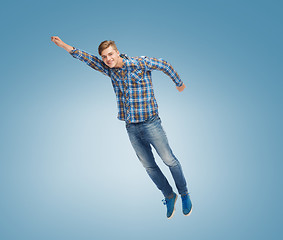 Image showing smiling young man jumping in air