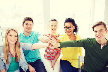 Image showing smiling students making high five gesture sitting