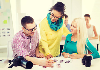 Image showing smiling team with printed photos working in office