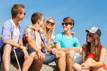 Image showing group of smiling friends sitting on city street