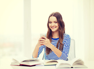 Image showing smiling student girl with smartphone and books