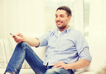 Image showing smiling man with tv remote control at home