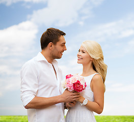 Image showing happy couple with flowers over natural background