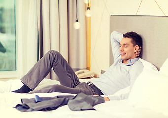 Image showing happy businesswoman lying in bed in hotel room