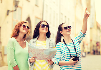 Image showing smiling teenage girls with map and camera