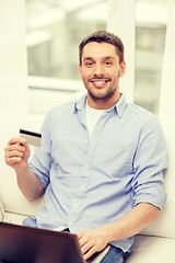 Image showing smiling man working with laptop and credit card