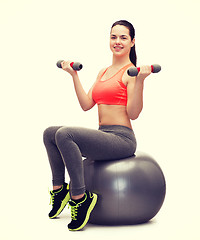 Image showing teenager with dumbbells sitting on fitness ball