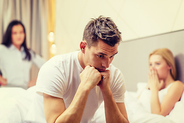 Image showing man sitting on the bed with two women on the back