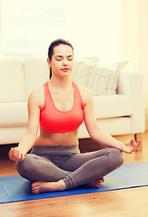 Image showing smiling teenager meditating at home