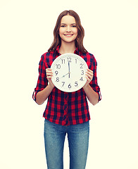 Image showing young woman in casual clothes with wall clock