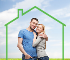 Image showing smiling couple hugging over green house