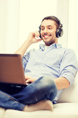 Image showing smiling man with laptop and headphones at home