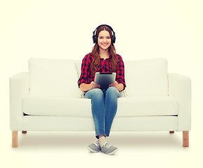 Image showing girl sitting on sofa with headphones and tablet pc