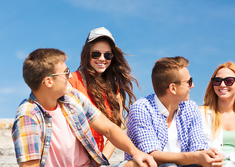 Image showing group of smiling friends sitting on city street