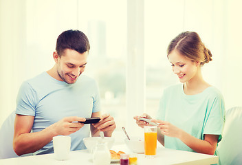 Image showing smiling couple with smartphones taking picture