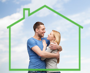 Image showing smiling couple hugging over green house