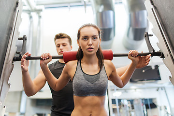 Image showing man and woman with barbell flexing muscles in gym
