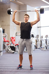 Image showing young man flexing muscles with barbell in gym